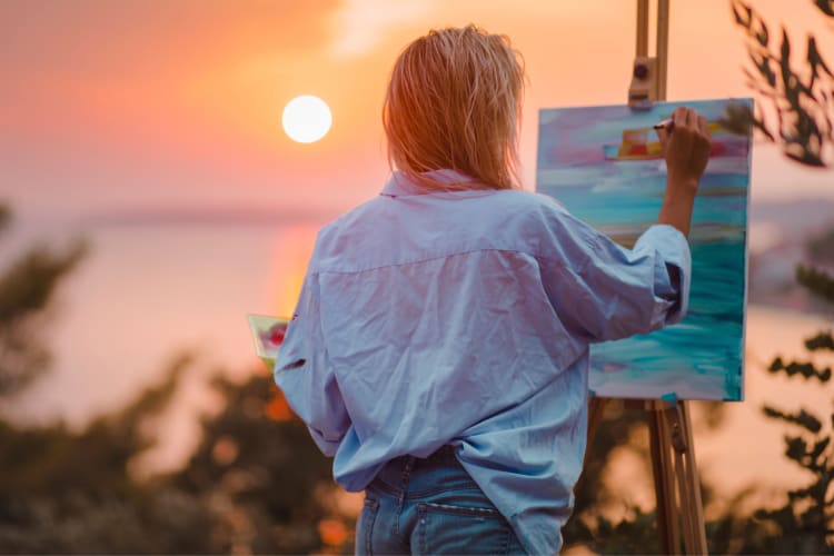 A person painting outside at sunset