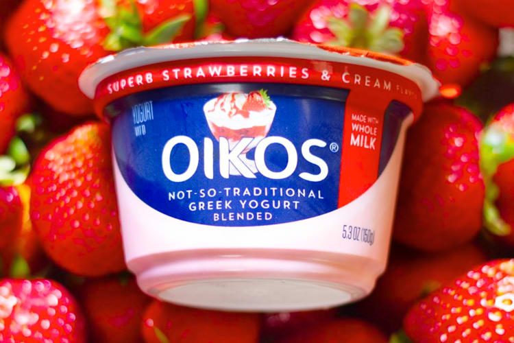 A pot of Oikos Greek yogurt on a bed of strawberries