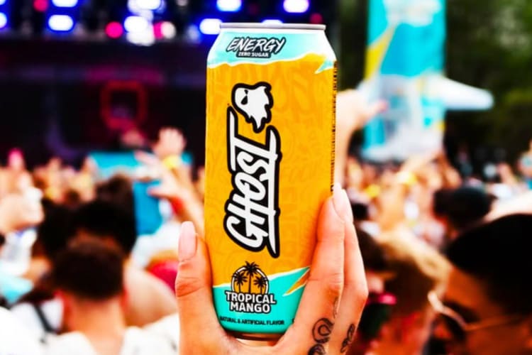 A person holding a Tropical Mango energy drink at a music festival