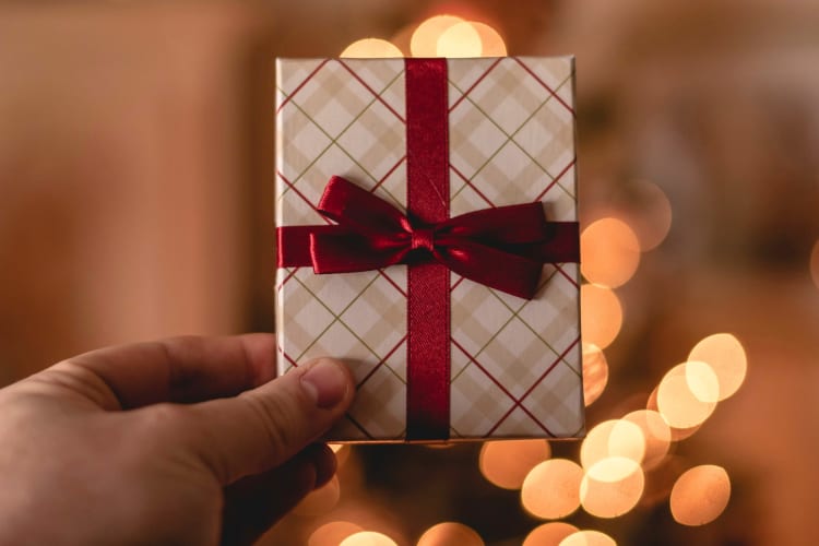 A person holding a gift card wrapped with a bow