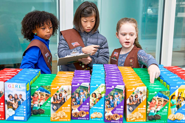 Three girls selling Girl Scout Cookies