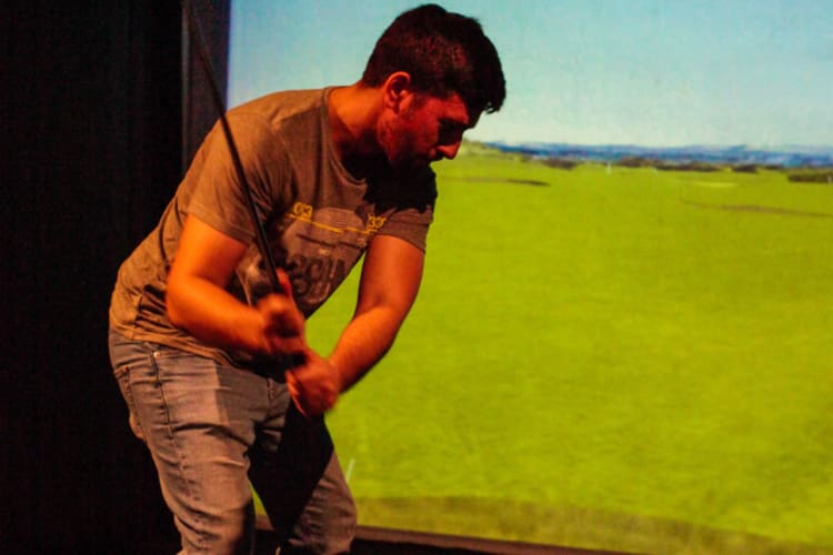 a man uses a golf simulator to play an indoor round of golf