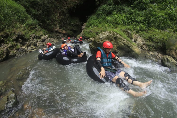 a group of people go tubing on rubber rings through a waterfall