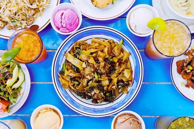 A Thai noodle dish and cocktails on a table