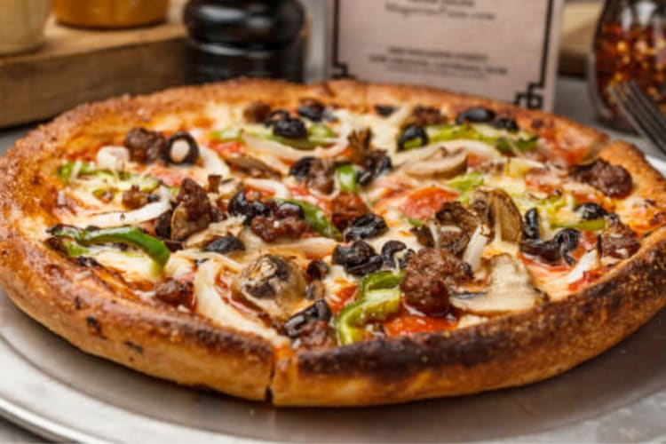 A well-cooked pizza with vegetables and meat