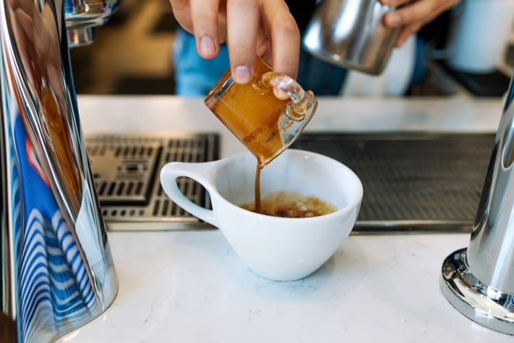 Close-up of a barista's hand pouring an espresso shot at Goshen Coffee