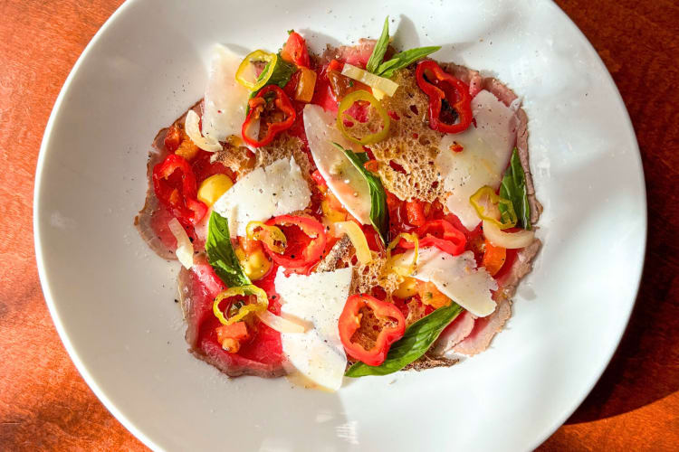Aerial view of beef carpaccio with shaved pecorino, peppers, and basil, from Gramercy Tavern