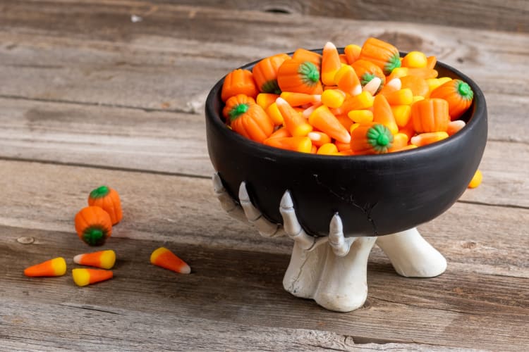 Candy corn and candy pumpkins in a Halloween-themed bowl