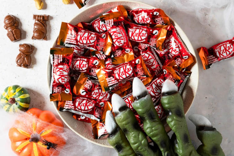 A bowl of mini Kit Kats next to Halloween decorations
