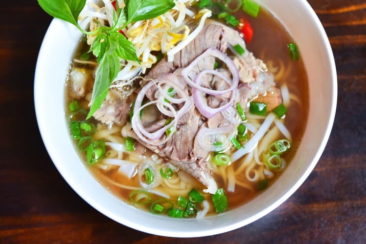 A bowl of noodle soup with beef and bean sprouts