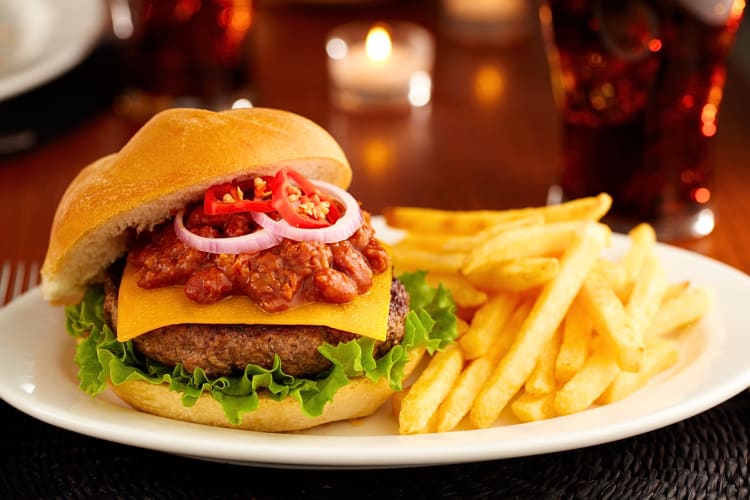 Burger with chili, cheese, onion and red peppers, on a plate with fries