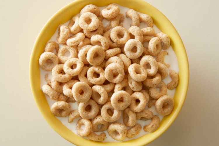 A yellow bowl with Cheerios and milk