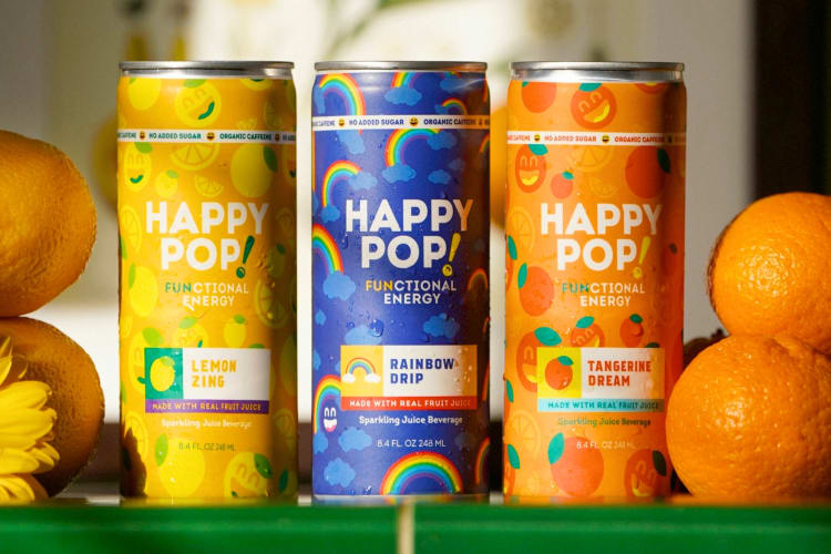 Cans of HappyPop next to oranges