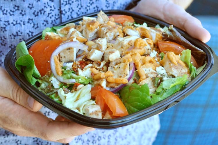 A person holding a take-out salad from Wendy's