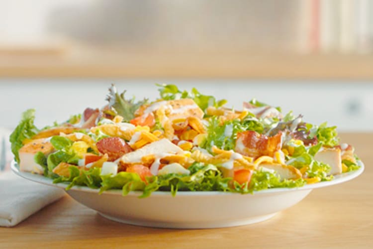 A bowl of Cobb salad on a wooden table