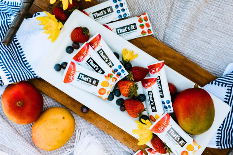 A tray with fresh fruit and snack bars in white packaging