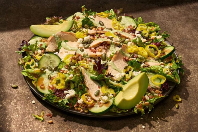 A salad with chicken, avocado, feta and pumpkin seeds