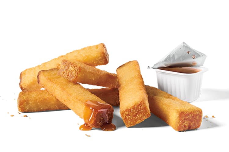 French toast sticks next to a cup of syrup