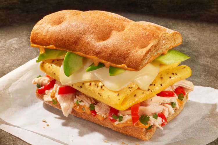 A ciabatta bread sandwich with eggs, avocado and chicken