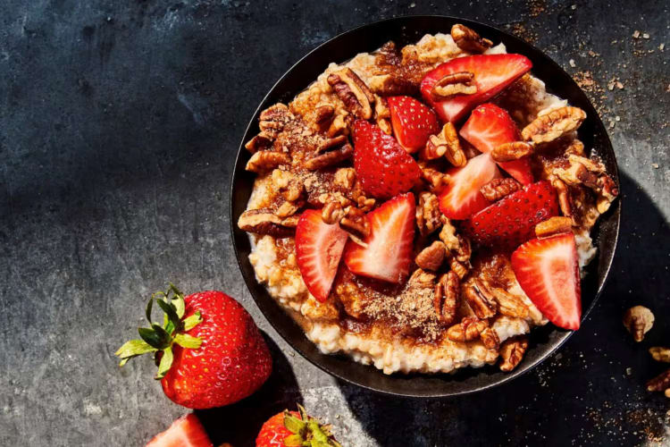 A bowl of oatmeal with strawberries and pecans