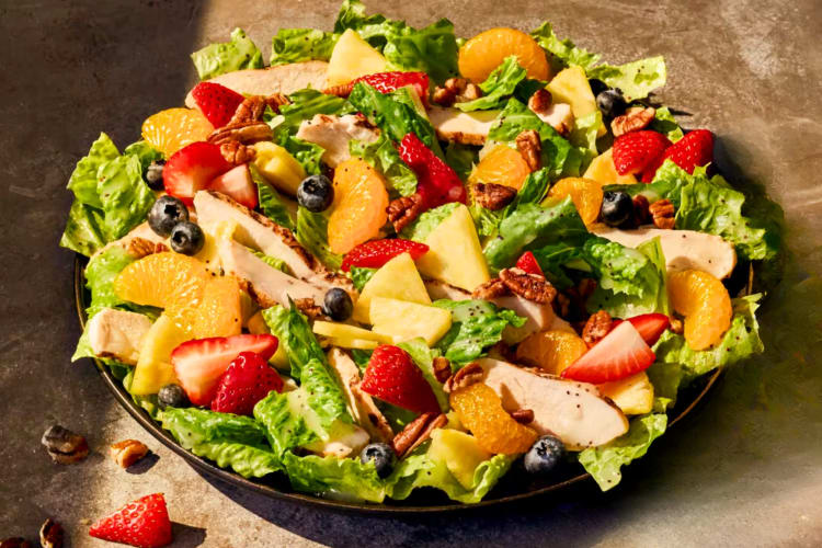 A salad with strawberries, oranges, pineapple, greens and chicken