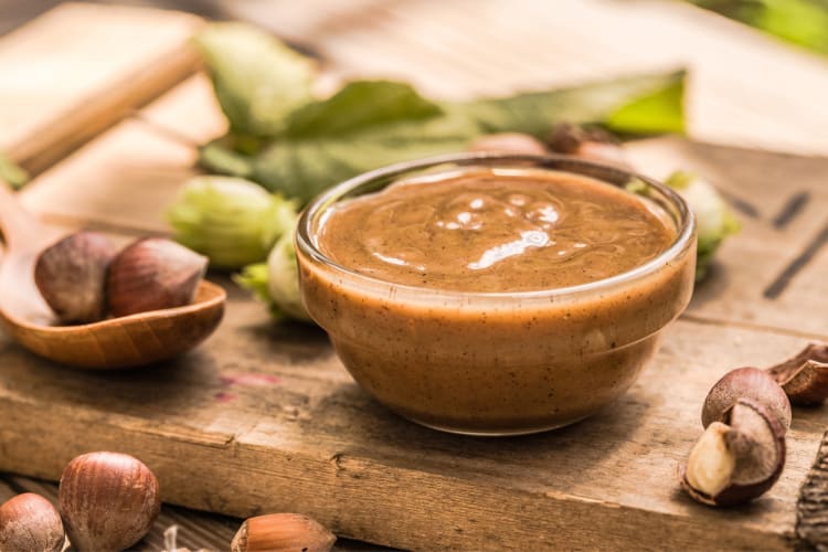 A bowl of hazelnut and raw hazelnuts