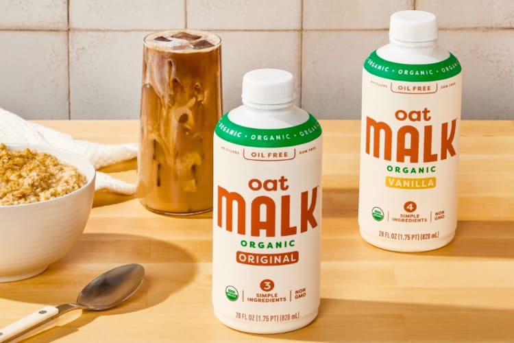 Bottles of oat milk on a table next to coffee and cereal