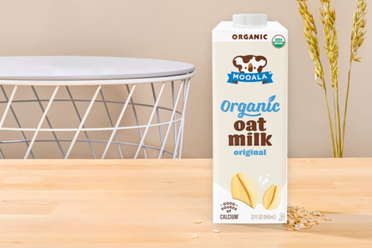A carton of oat milk with a koala character on a wooden countertop