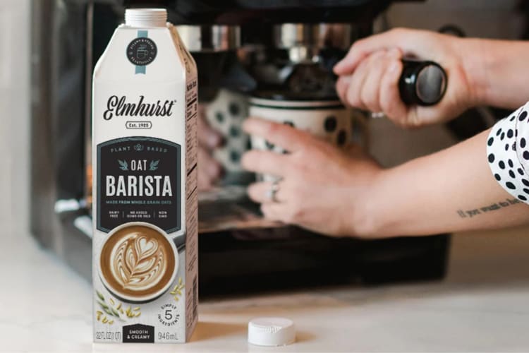 A carton of oat milk next to a coffee machine