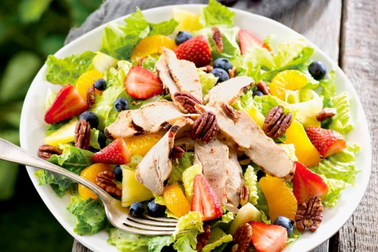 A salad with fresh fruits, chicken and pecans