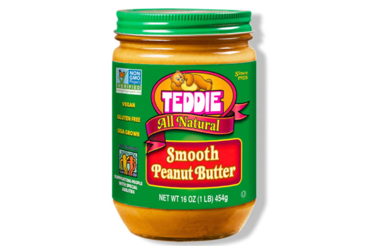 A glass jar of peanut butter with green branding and a teddy bear logo