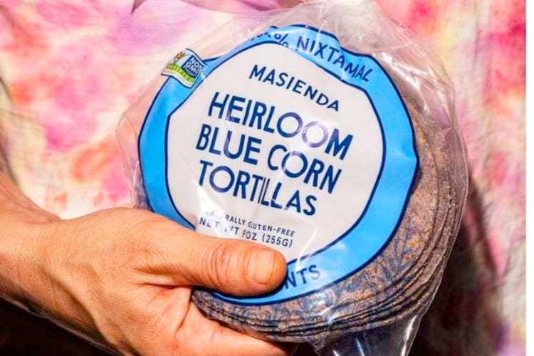A person holding a bag of heirloom blue corn tortillas