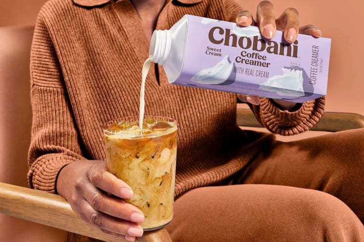 A person pouring Chobani creamer into coffee