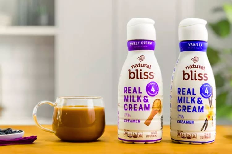 Two containers of coffee creamer next to a cup of coffee