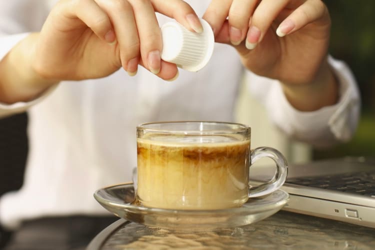 A person pouring creamer into a coffee