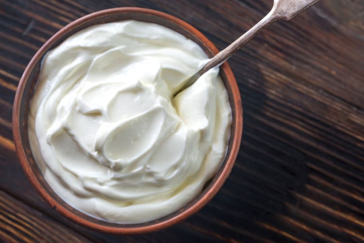 A bowl of Greek yogurt on a wooden surface
