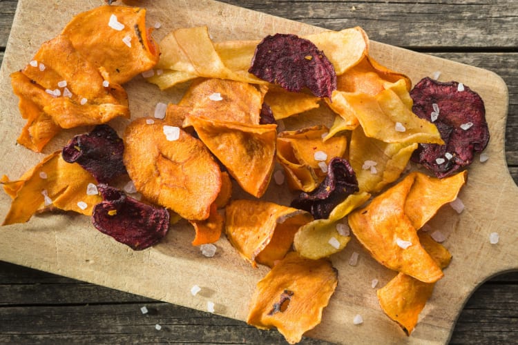 Vegetables chips on a board with sea salt