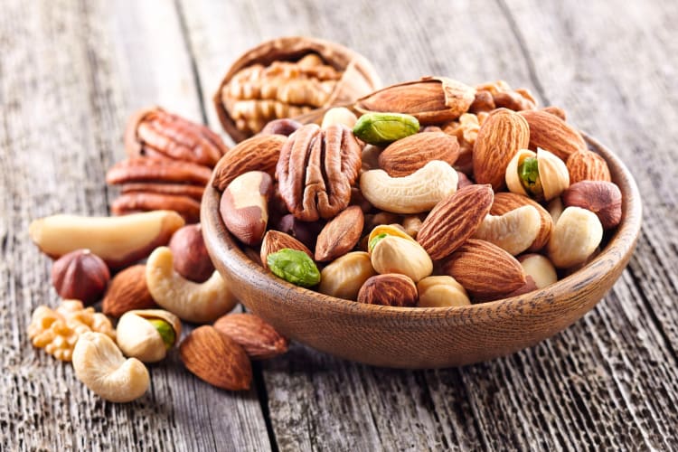 A bowl of mixed nuts on a wooden surface