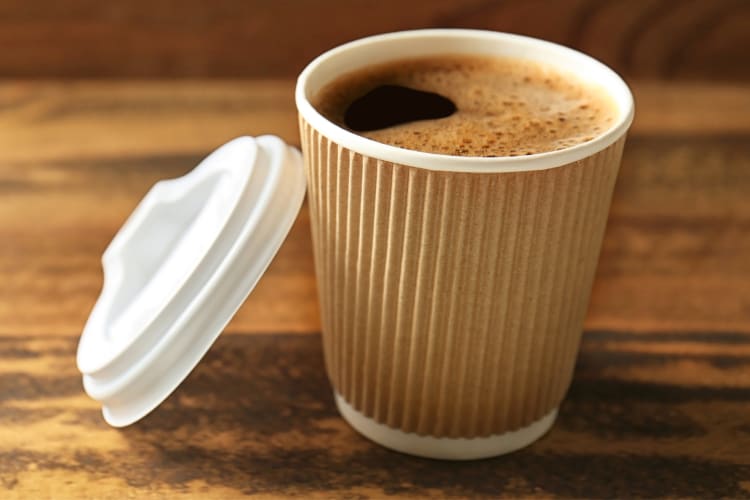 A take-out cup of coffee on a wooden table