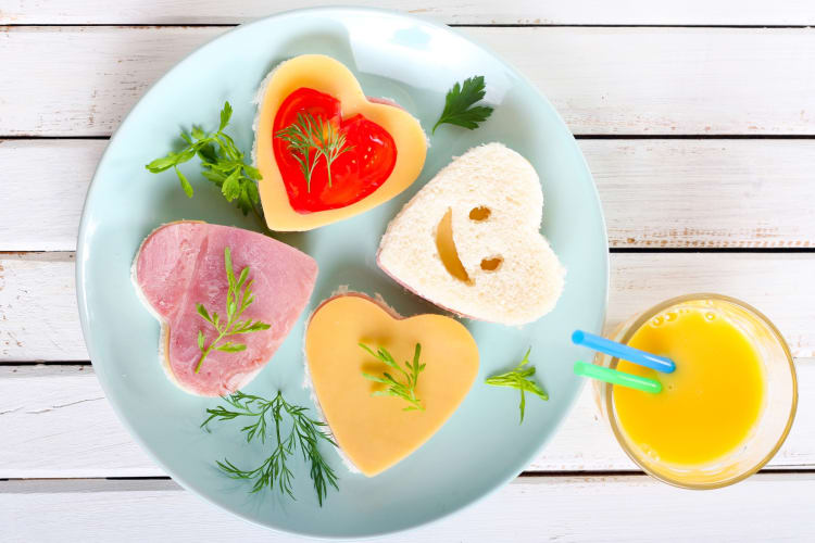 Heart shaped-sanwiches on a blue plate and a glass of juice