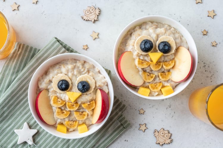 Bowls of oatmeal with owls decorations made of fruits and nuts