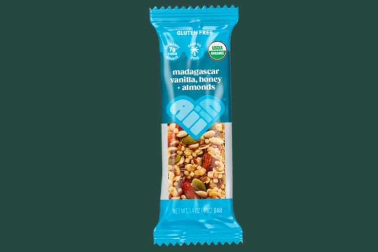 A granola bar in a blue packet on a green background