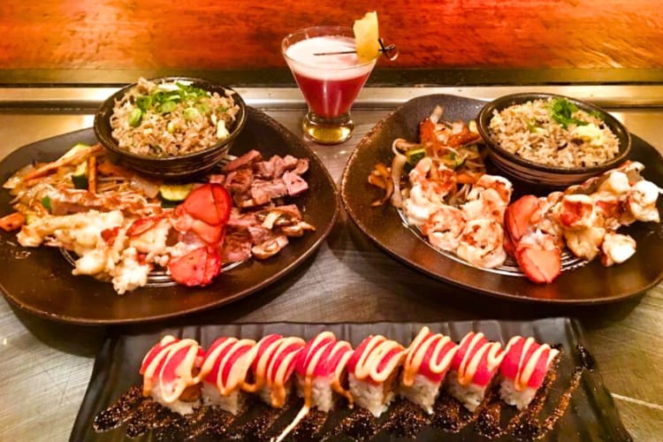 Two hibachi plates, a plate with sushi and a cocktail