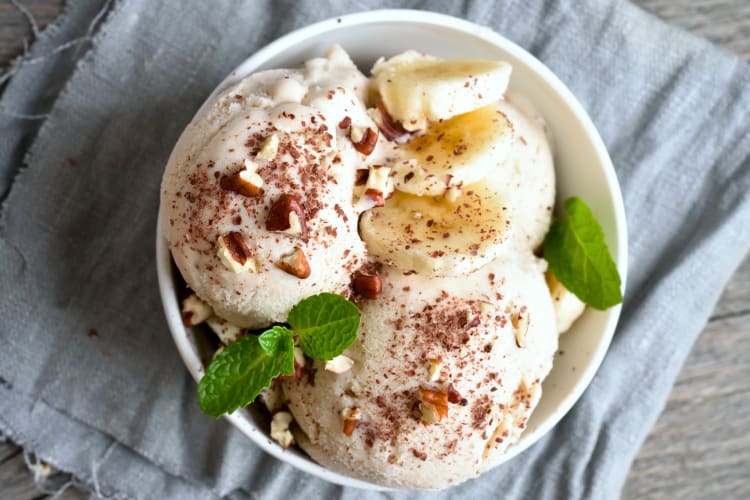 A bowl of ice cream with bananas and nuts