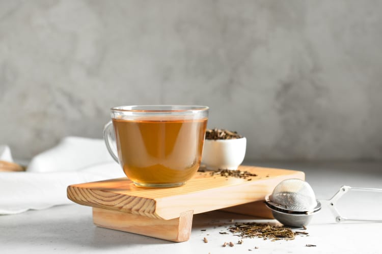 Hojicha tea in a glass cup next to dried hojicha