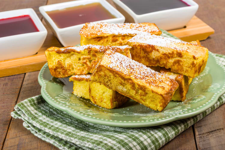 French toast sticks with three different sauces in the background