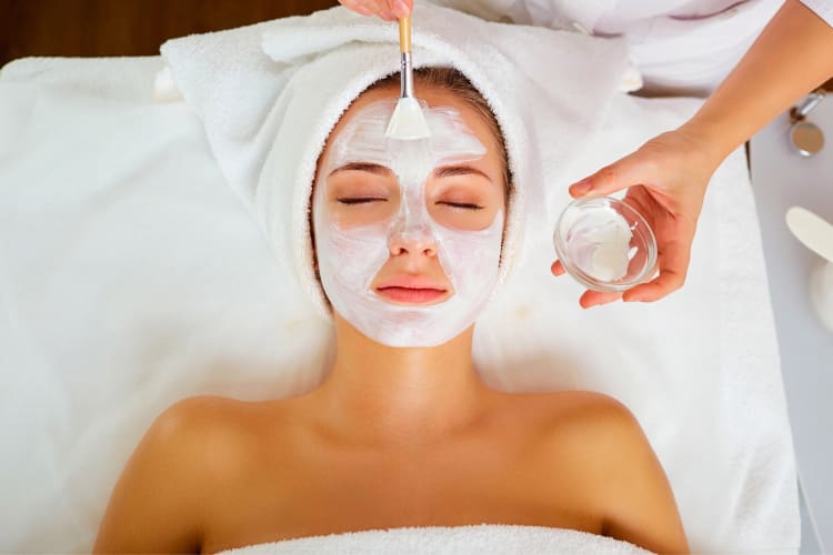 A woman having a face mask put on at a spa