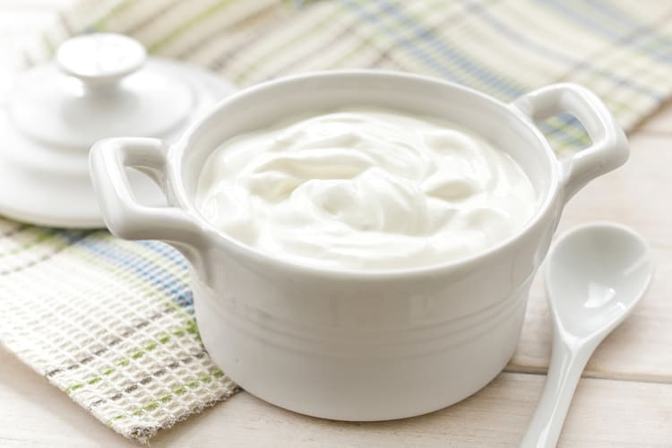 Sour cream in a white ceramic tuppwerware, next to a white spoon