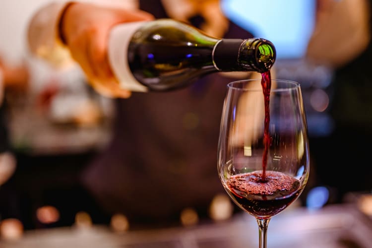 A person pouring red wine into a glass