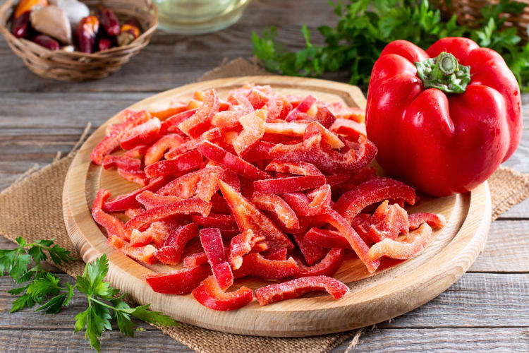 Frozen chopped bell pepper pieces next to a whole bell pepper